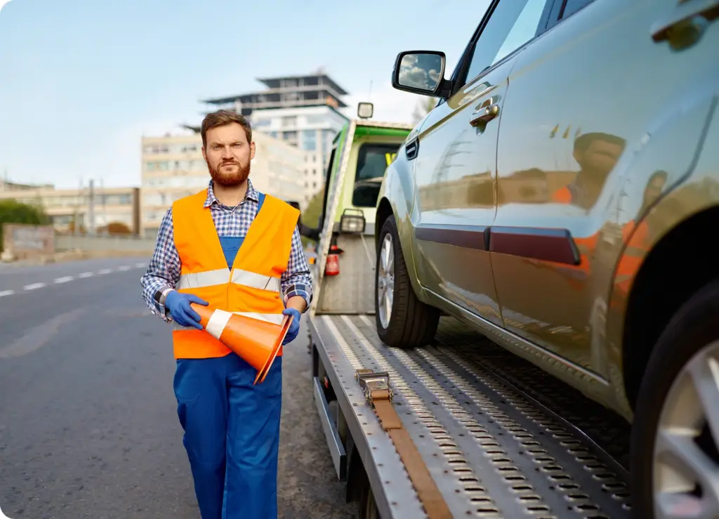7 Essential Car Services You Can Book From Your Phone A roadside service man in a vest and gloves holding a cone next to a car-on-demand car service by Revilo Auto Care