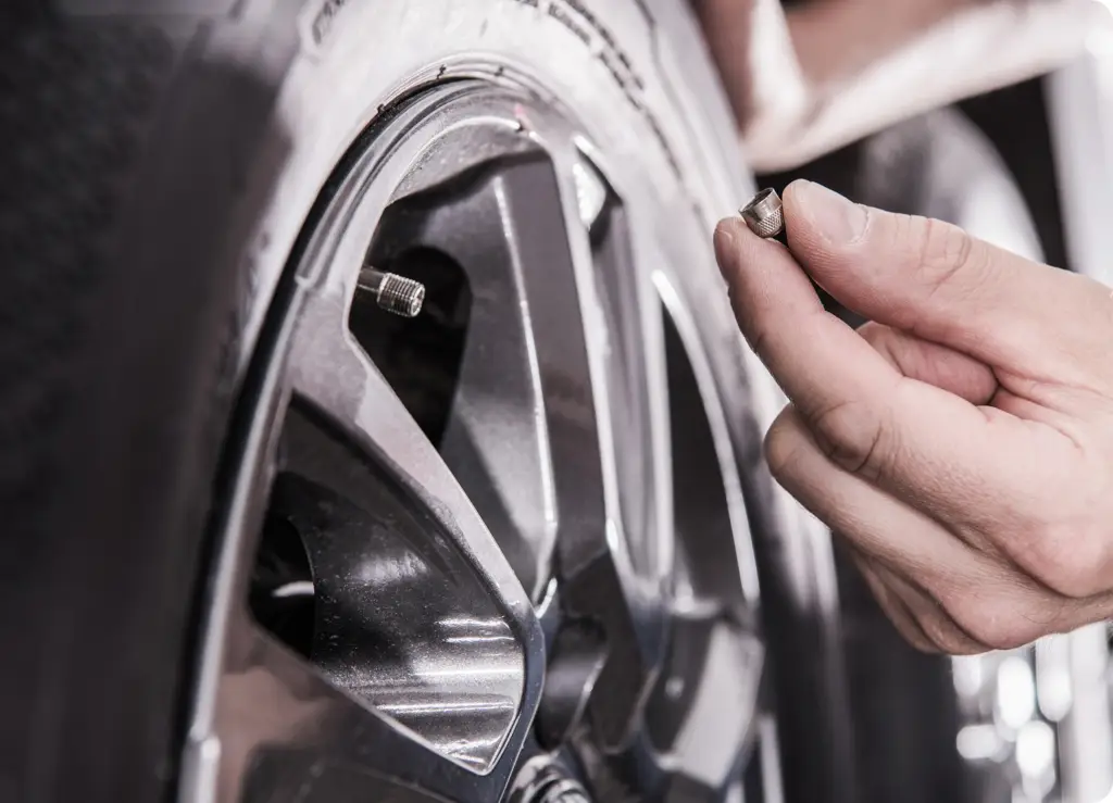 7 Essential Car Services You Can Book From Your Phone a person holding a screw in a tire for service -on-demand car service by Revilo Auto Care